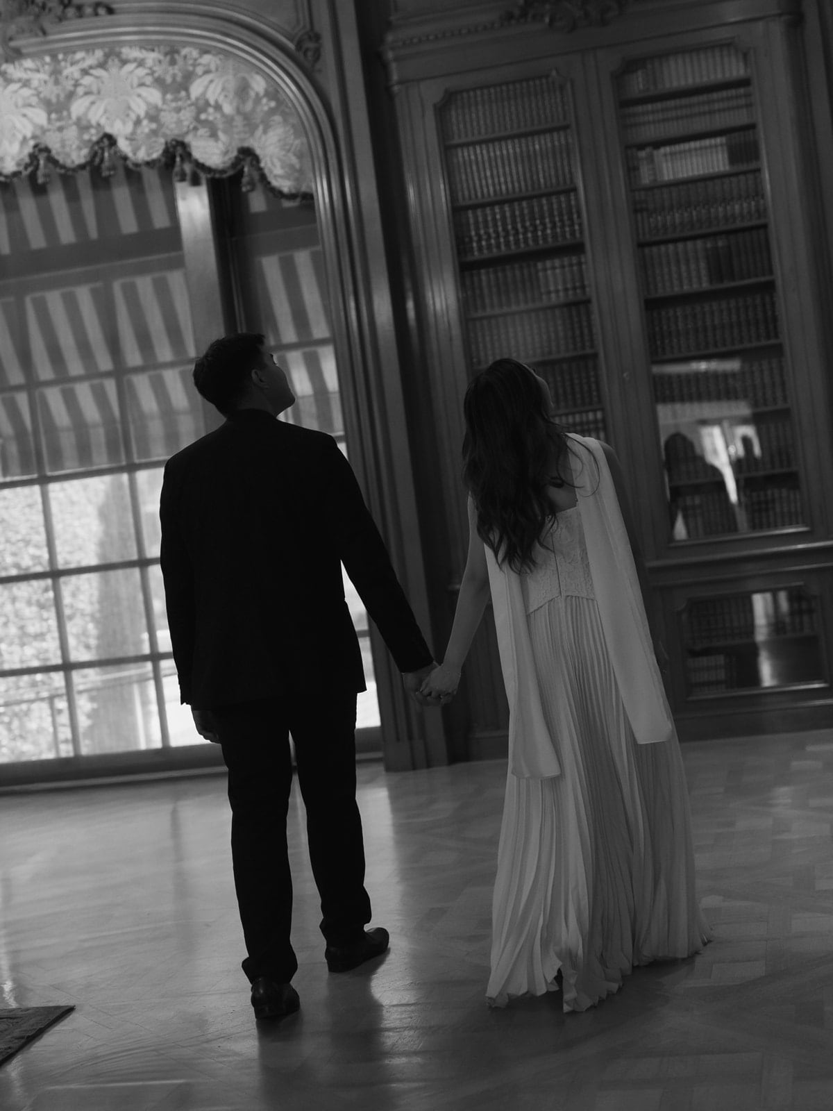 Edwin and Grace walking through a warm library during their engagement shoot