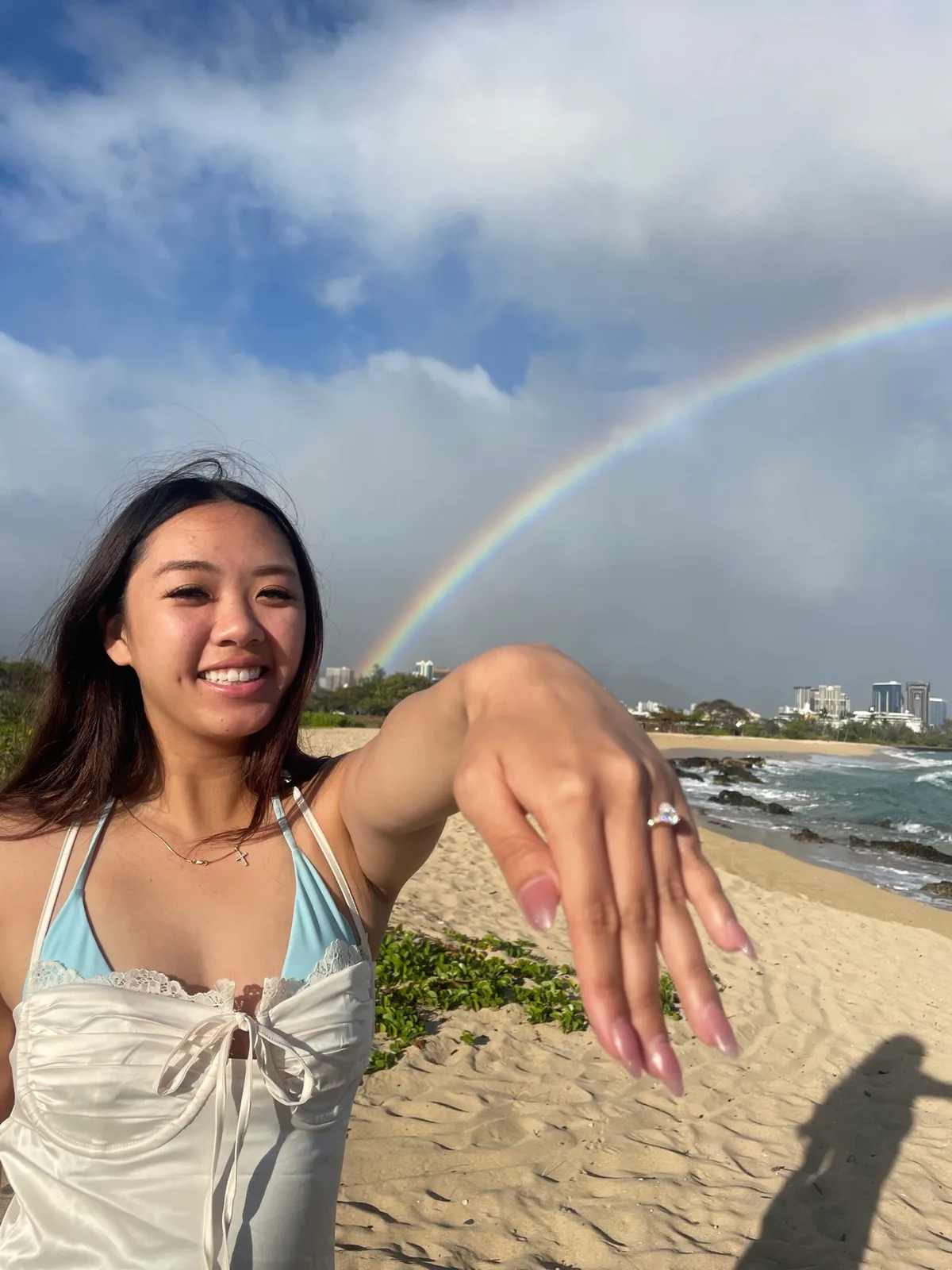 Grace showing her engagement ring under a rainbow in Hawaii